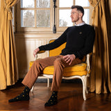 homme assis dans un fauteuil, portant un pull napoléon noir et une paire de chaussettes Napoléon noires Maison Broussaud