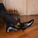 homme élégant portant des chaussettes Napoléon avec un aigle impérial près d'un échiquier