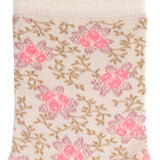 Détail du motif floral rose et beige sur chaussette femme moyenne blanche.