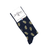 Chaussettes homme mi-hautes bleu marine motif mimosa jaune, emballées sous étiquette Maison Broussaud.