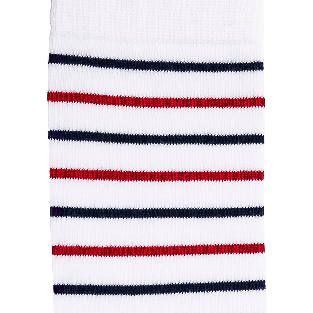 Détail des rayures rouges et bleues sur chaussette homme haute blanche.