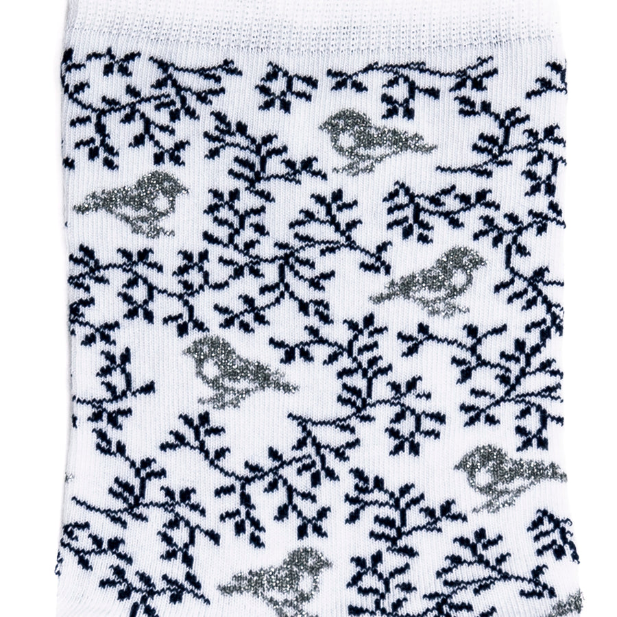 Détail du motif oiseaux gris et branches noires sur chaussette femme blanche.