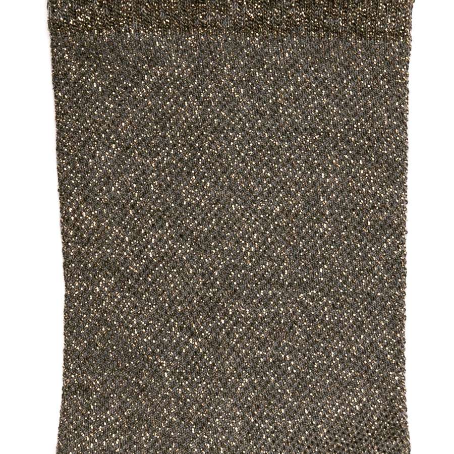 Détail de la maille brillante dorée sur chaussette femme moyenne.